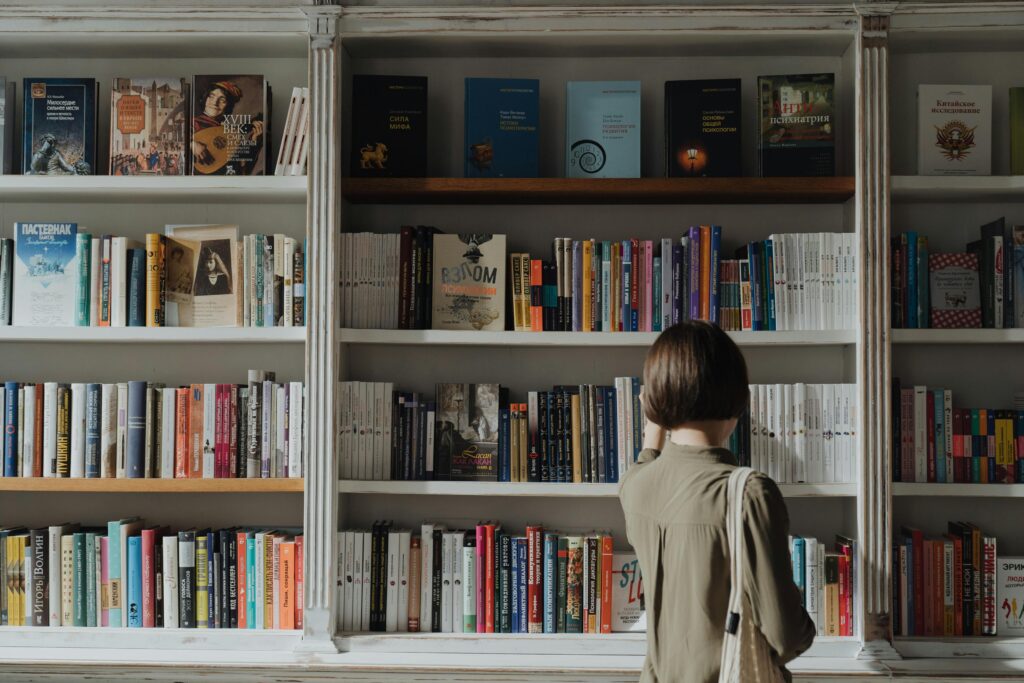 A woman browsing a large book collection in a cozy bookstore, exploring literature.
